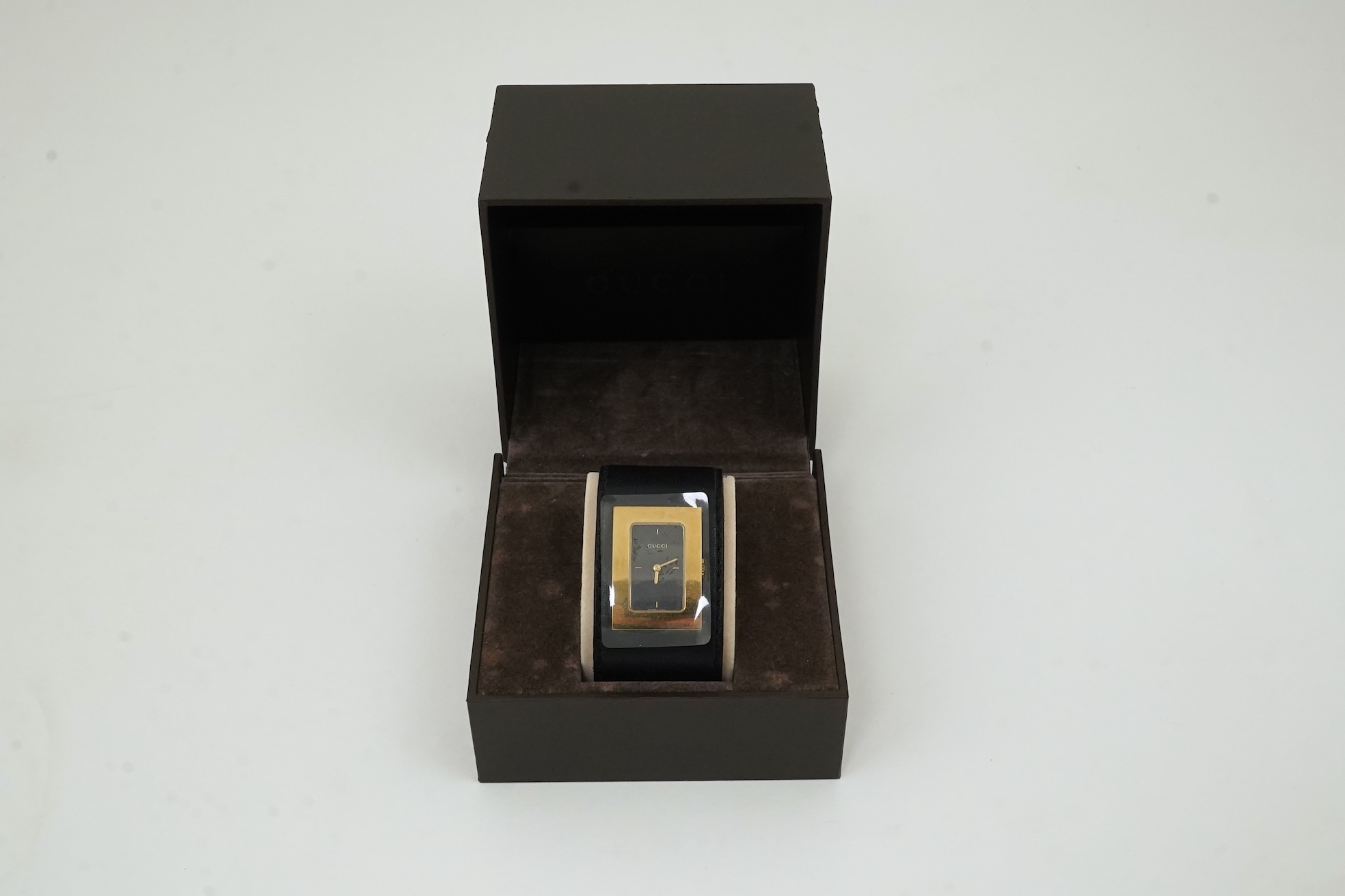 A lady's Gucci watch with wide leather strap, with box and papers.